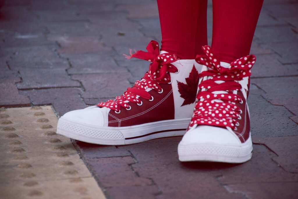 Close-up of red sneakers with Canadian maple leaf pattern on stone pavement. Outdoor fashion shot.